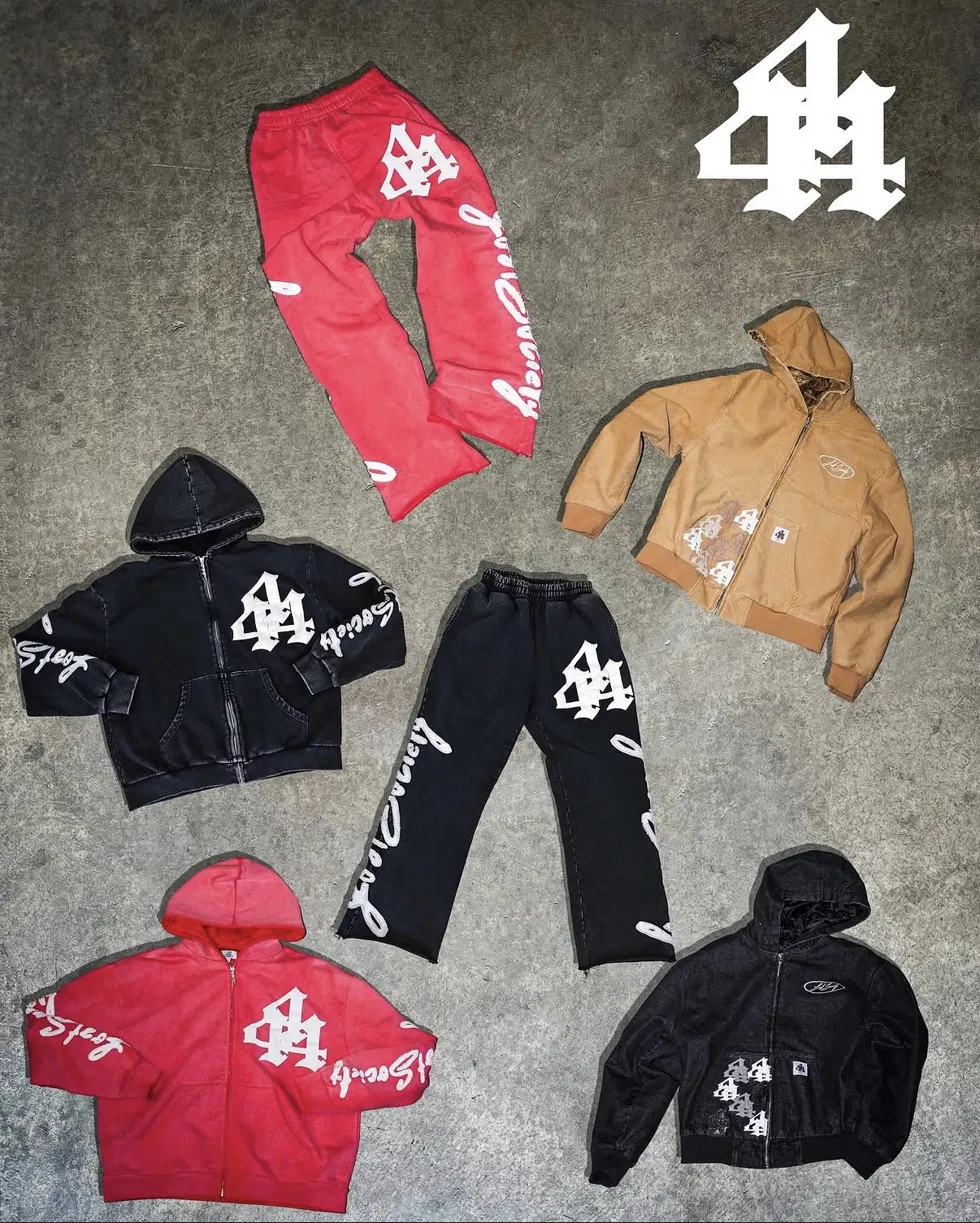 Flat lay of the Lost Society collection: red and black hoodies and sweatpants, a tan Carhartt-style jacket, and a black jacket, all printed with the 44 mark