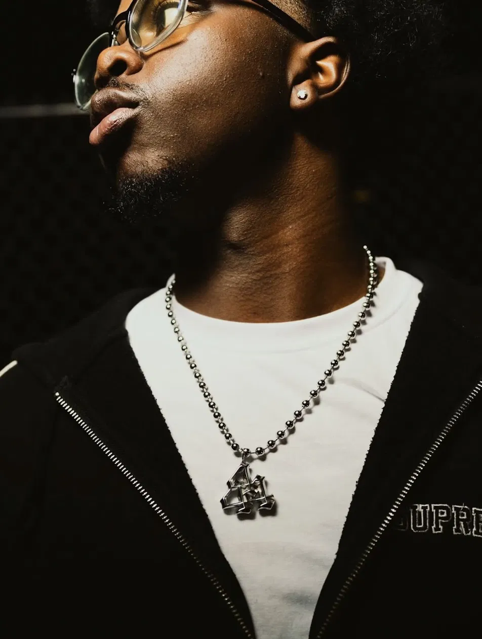 Model wearing a silver 44 pendant on a ball chain over a white tee and black hoodie
